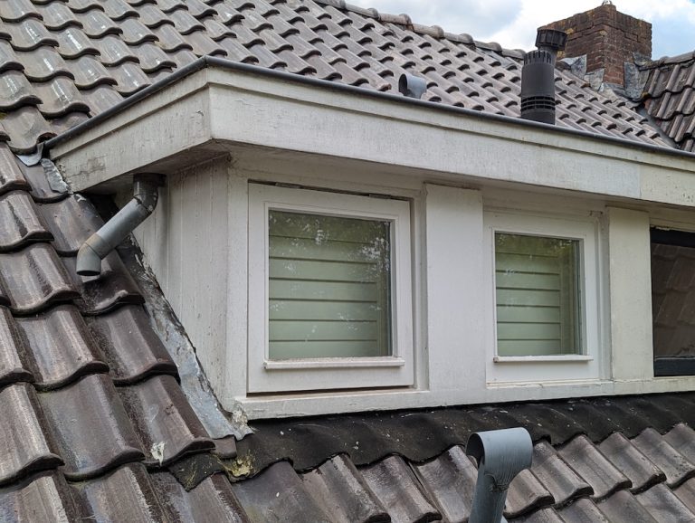 Verweerde dakkapel met afbladderende verf voor aanpak