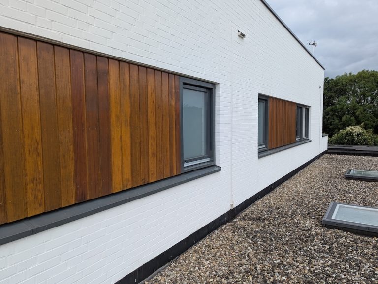 Hardhouten gevelpanelen naast wit geschilderd metselwerk