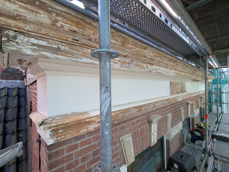 Kroonlijst met loslatende verf en aangetast hout voor herstel