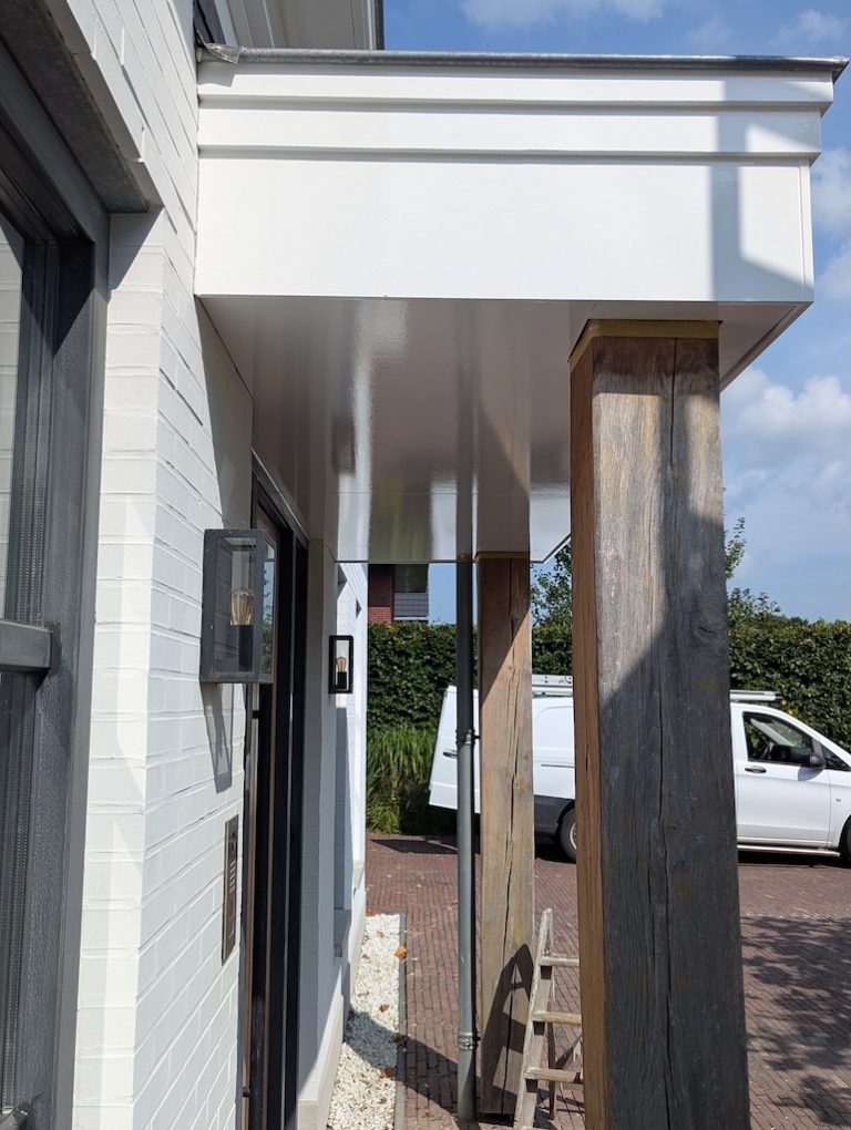 Overdekte entree met houten kolom en wit stucwerk