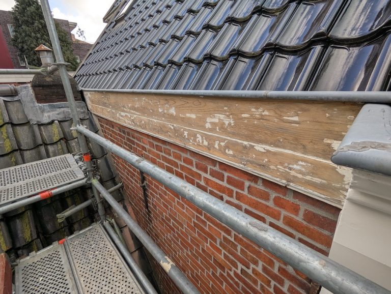 Kaal houten daklijst boven metselwerk voor behandeling