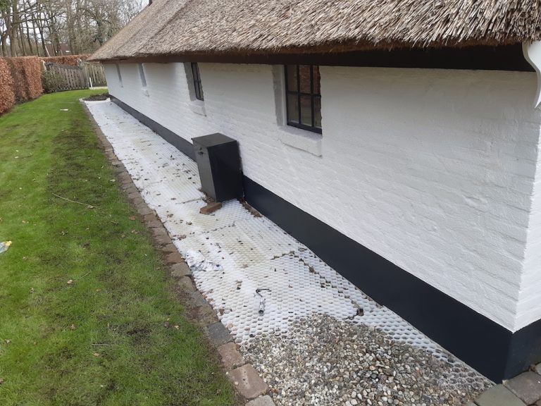 Wit geschilderde rietgedekte boerderij met zwarte plint